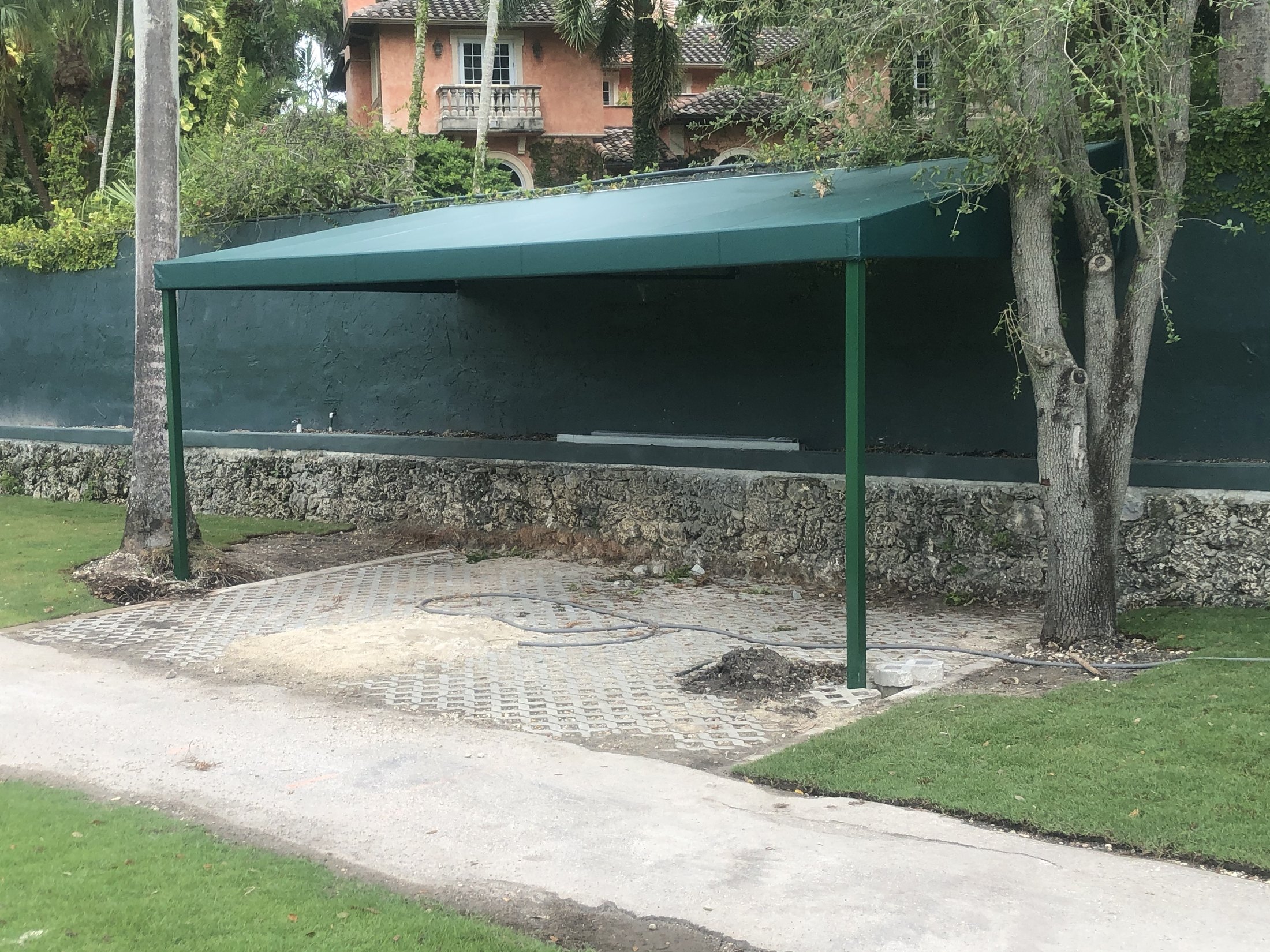 Compact green carport designed around the available driveway